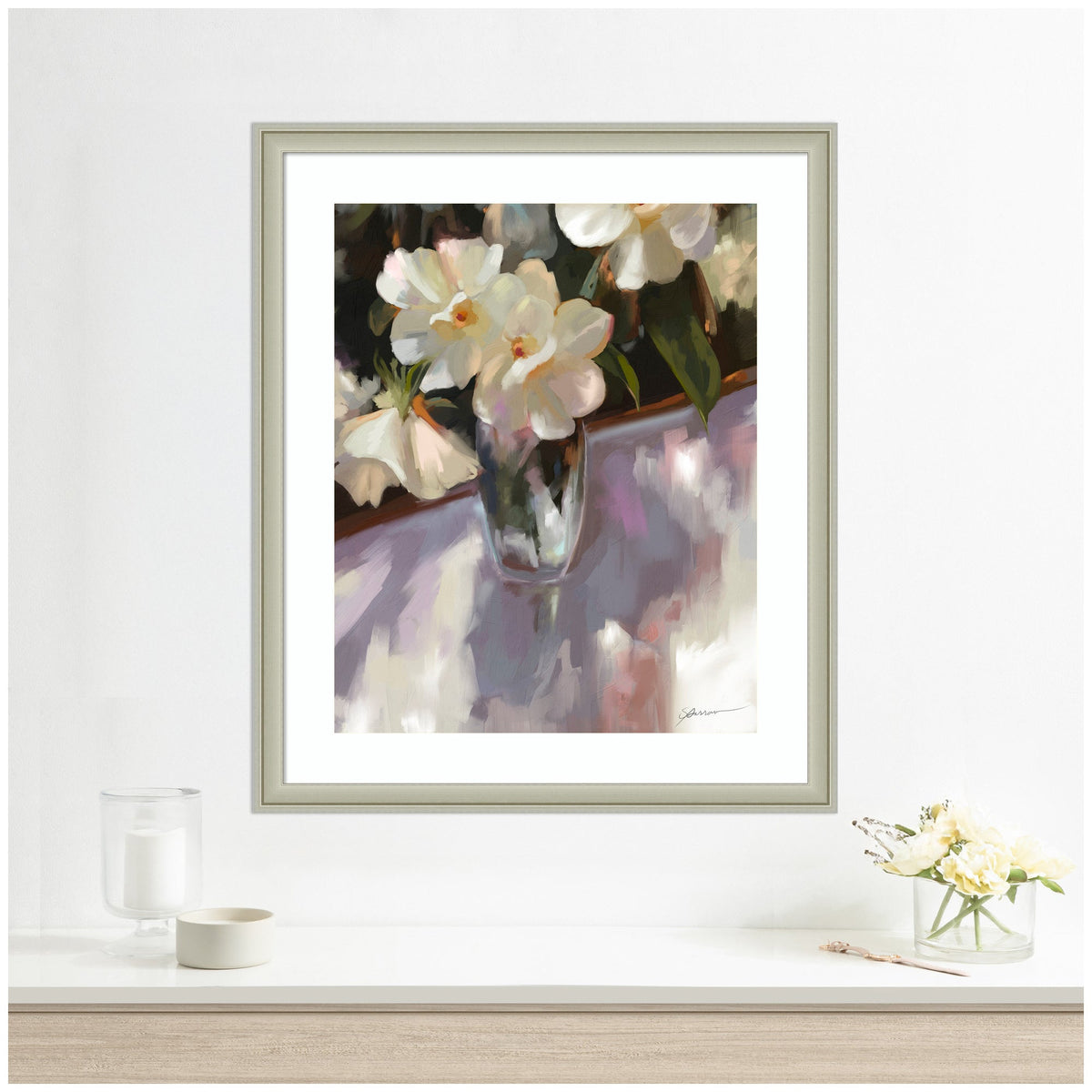 Framed artwork of flowers on a white wall with candles and a vase.