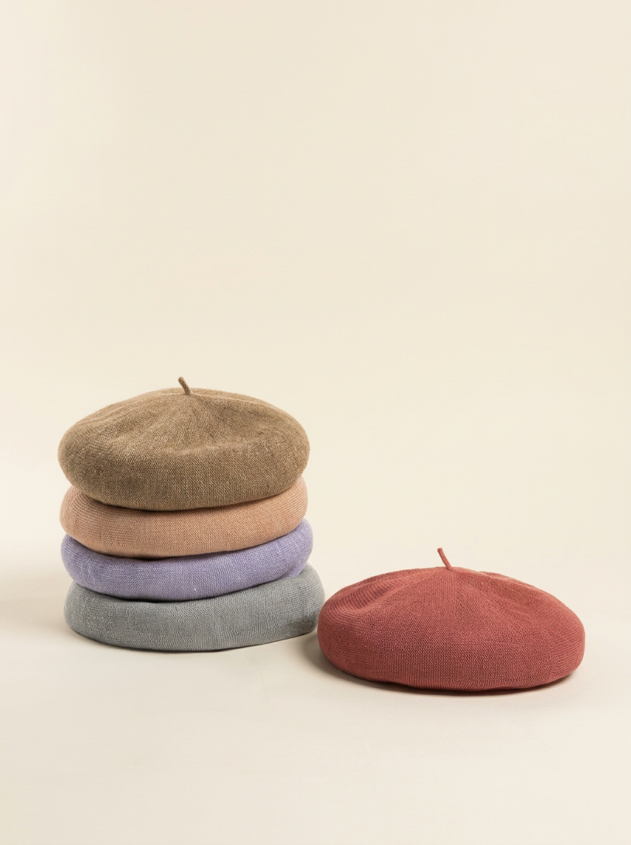 Stack of berets in various colors on a beige background