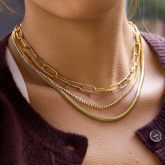 Close-up of a person wearing two gold necklaces with a blurred background