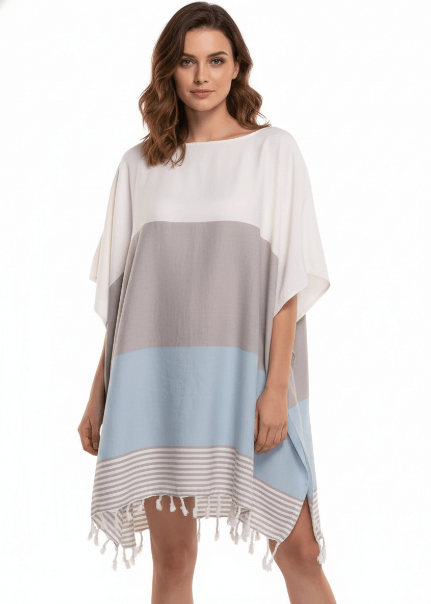 Woman wearing a color-blocked poncho with white, gray, and light blue sections on a white background.
