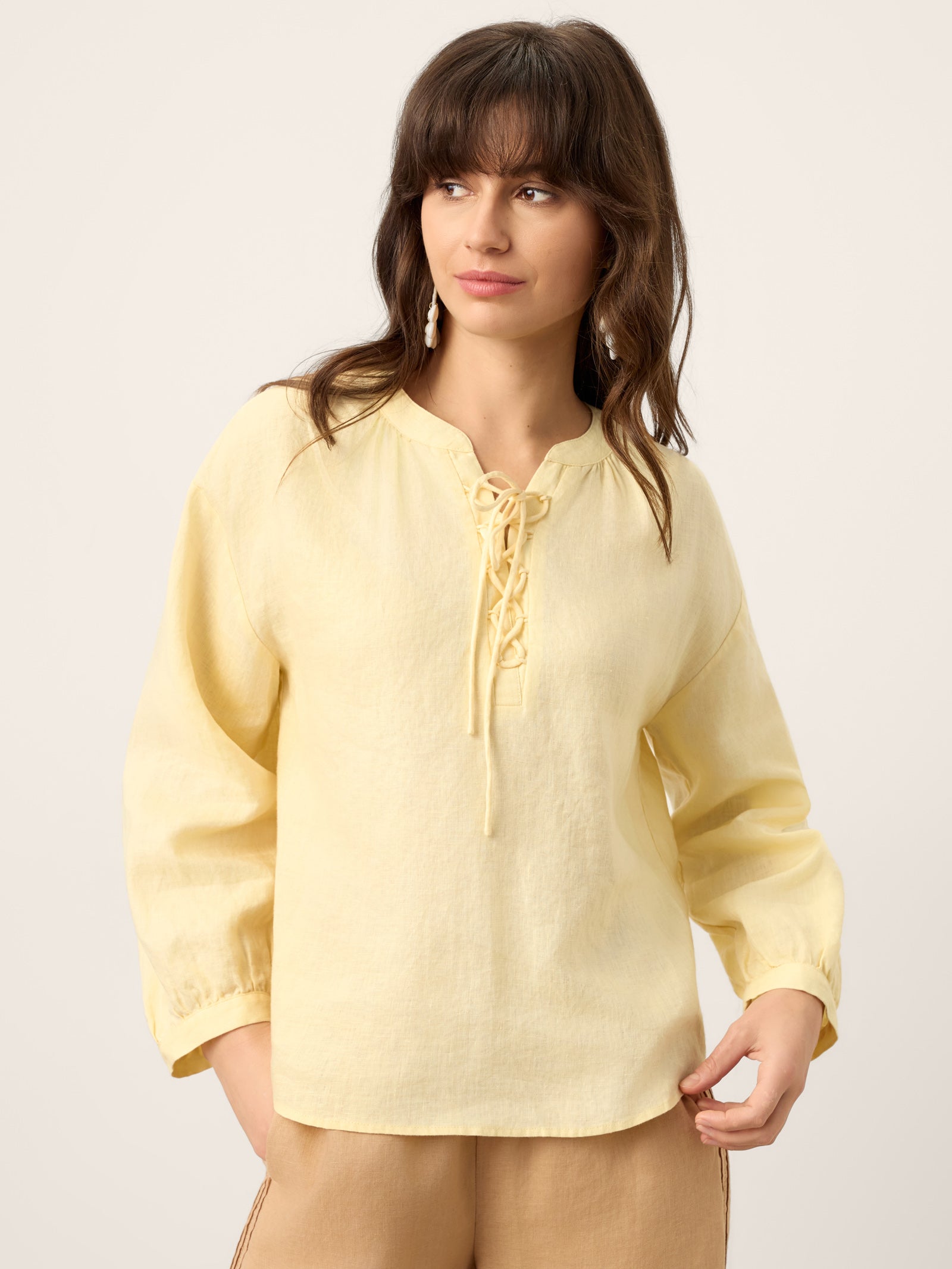 Woman wearing a light yellow blouse with a plain background
