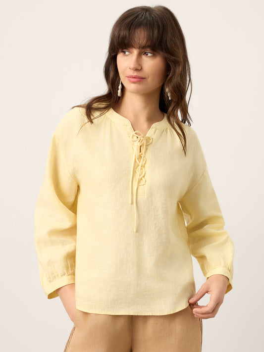 Woman wearing a light yellow blouse with a plain background