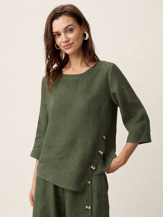 Woman wearing a green linen top with buttons on a beige background
