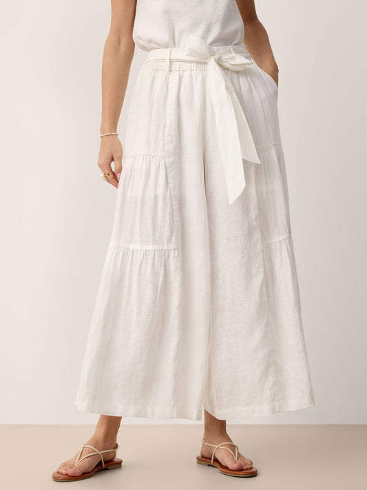Person wearing a long white skirt with a plain background