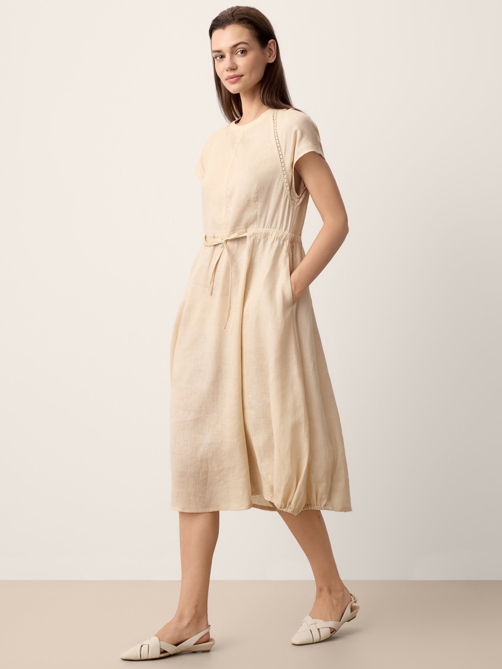 Woman wearing a beige dress against a plain background
