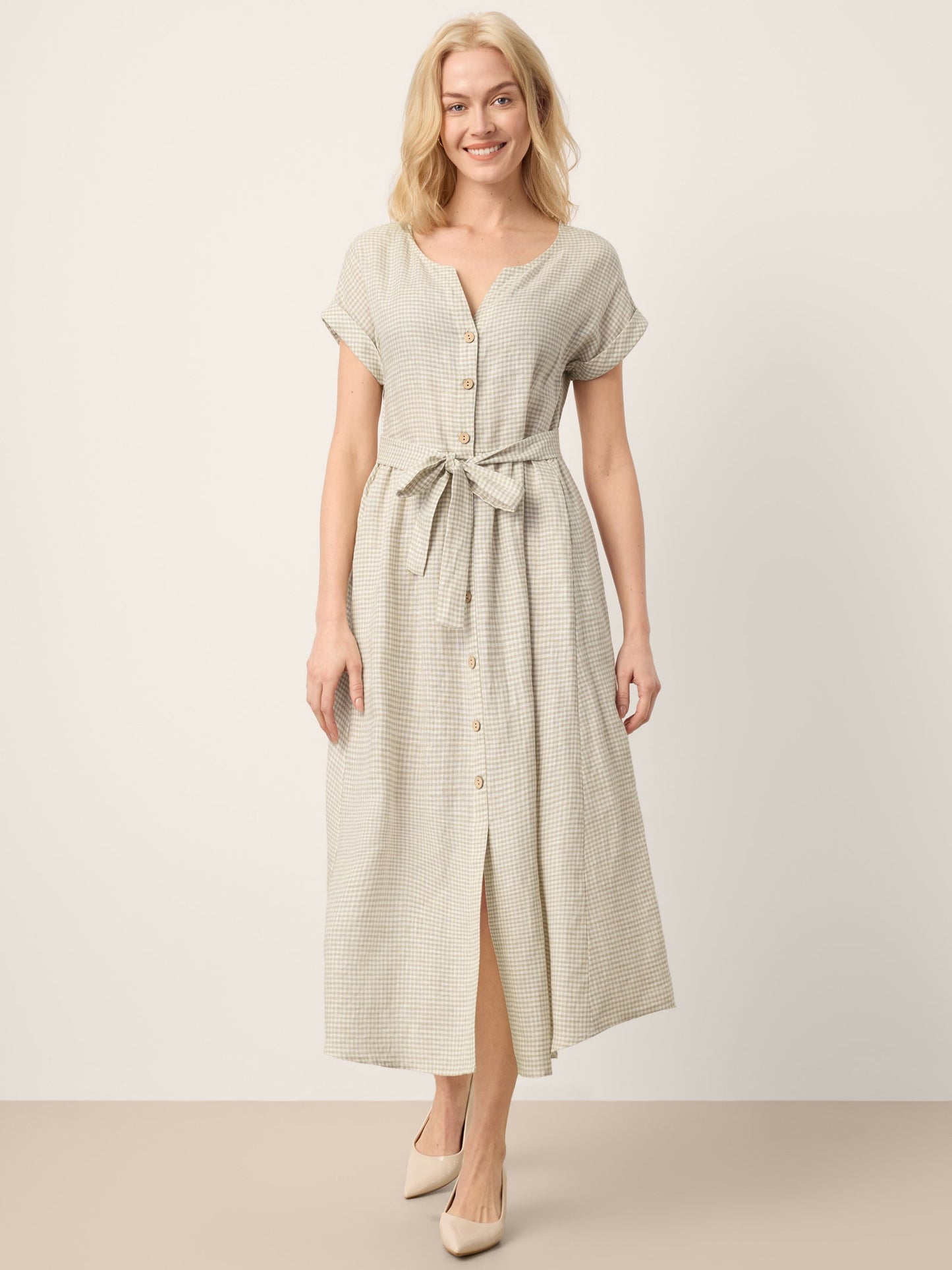 Woman wearing a light green dress with a belt against a white background