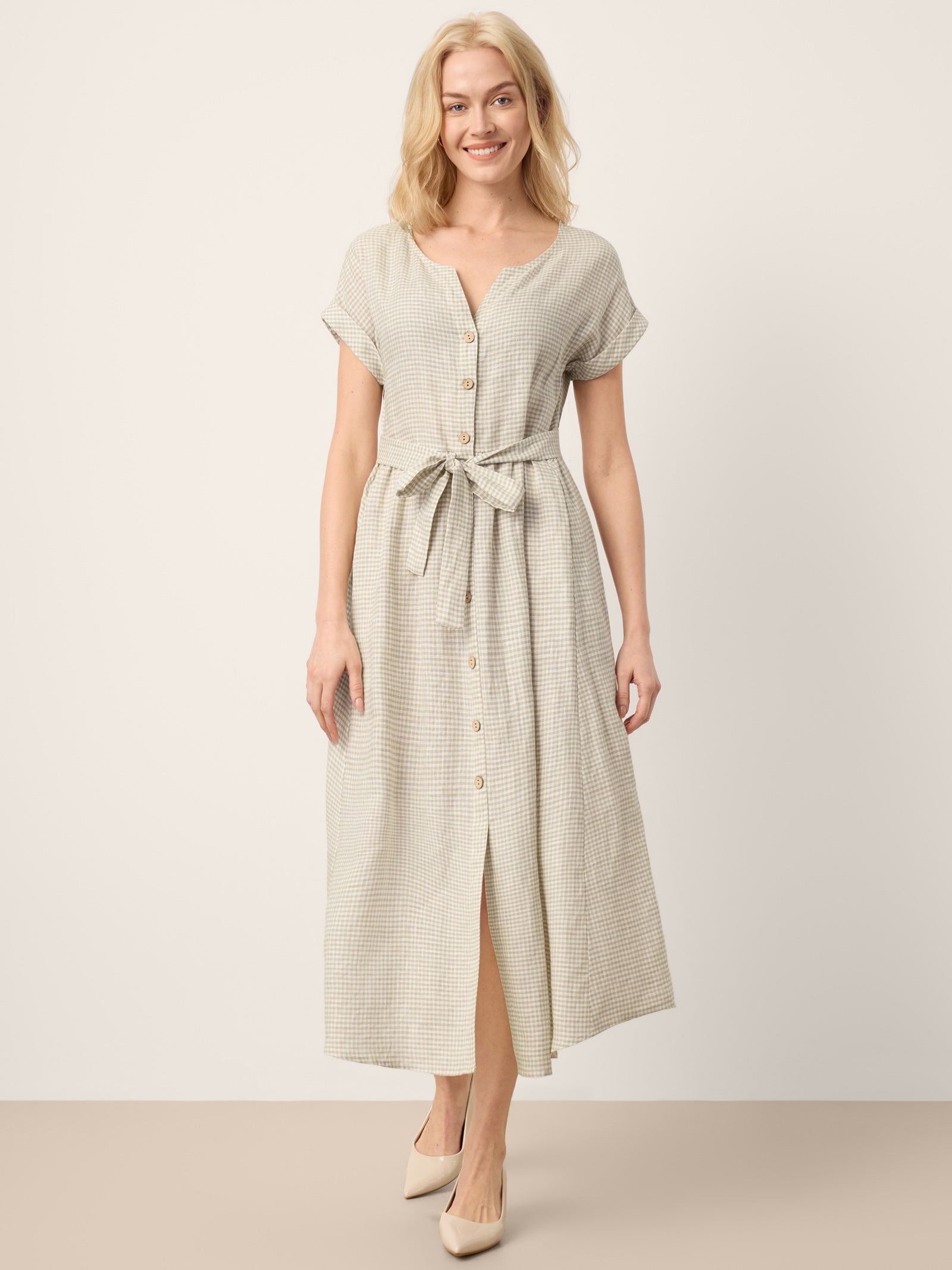 Woman wearing a light green dress with a belt against a white background