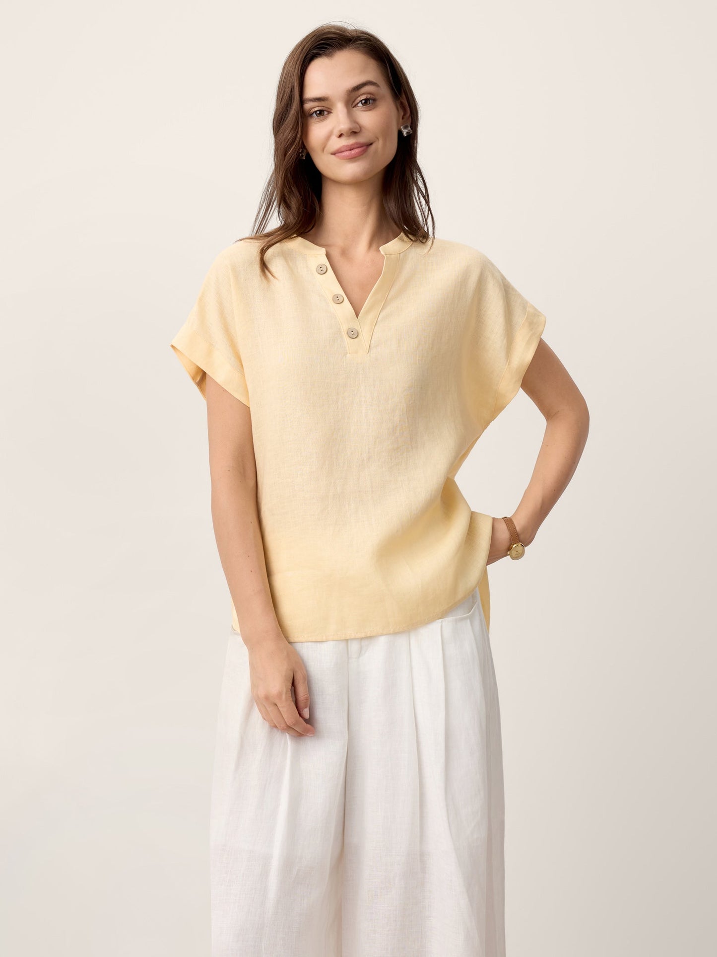 Woman wearing a light yellow blouse and white pants on a beige background