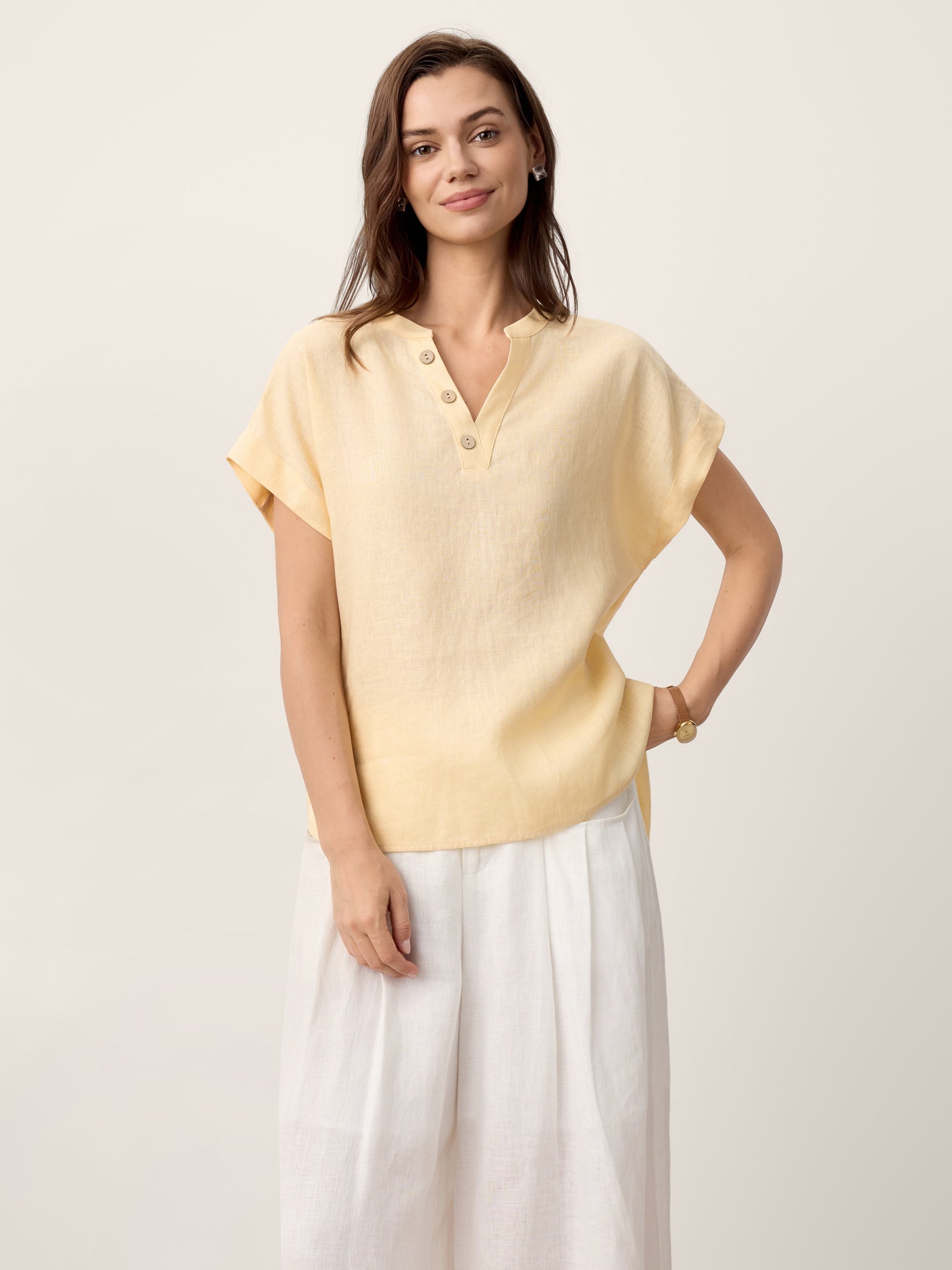 Woman wearing a light yellow blouse and white pants on a beige background