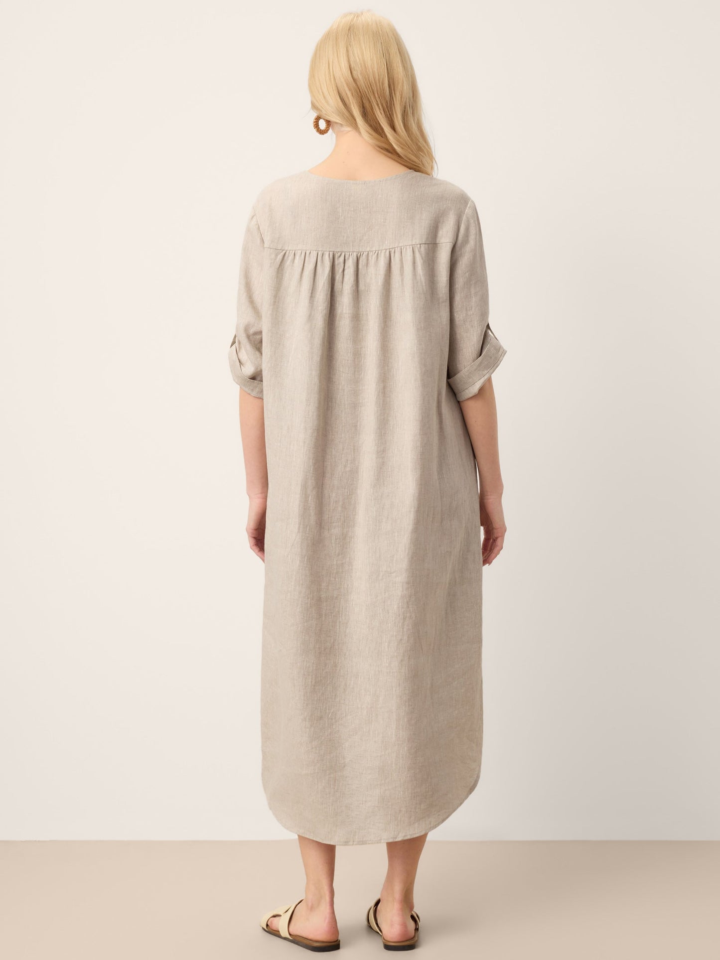 Woman wearing a long beige dress against a white background