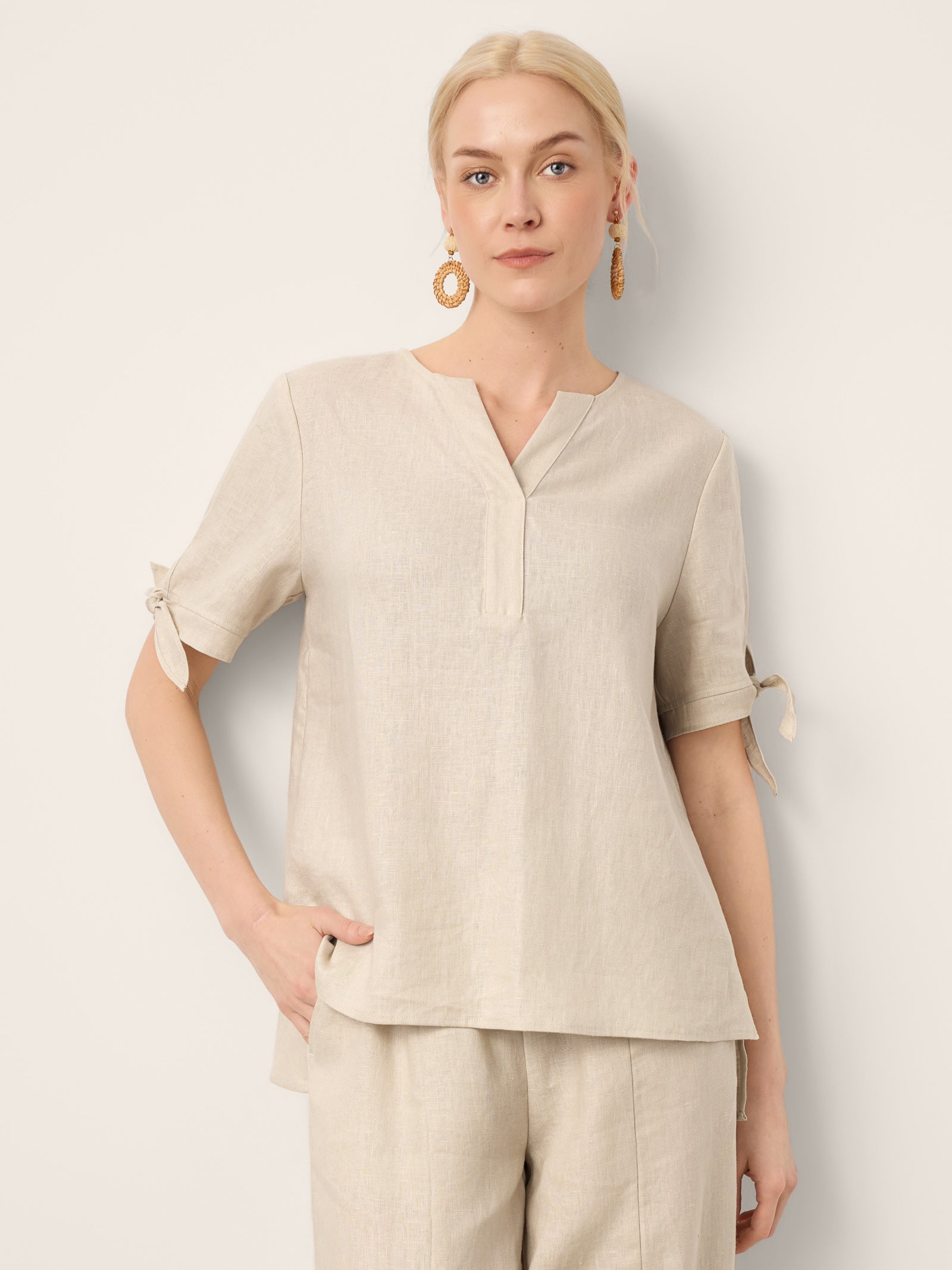 Woman wearing a beige top and pants against a light background
