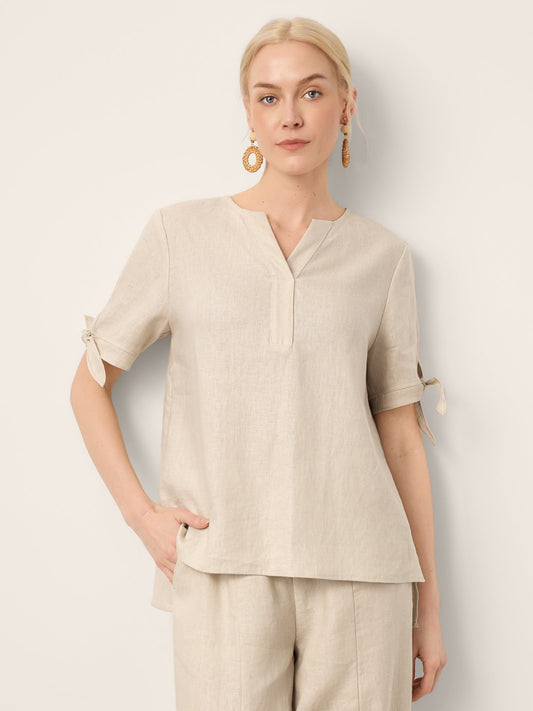 Woman wearing a beige top and pants against a light background