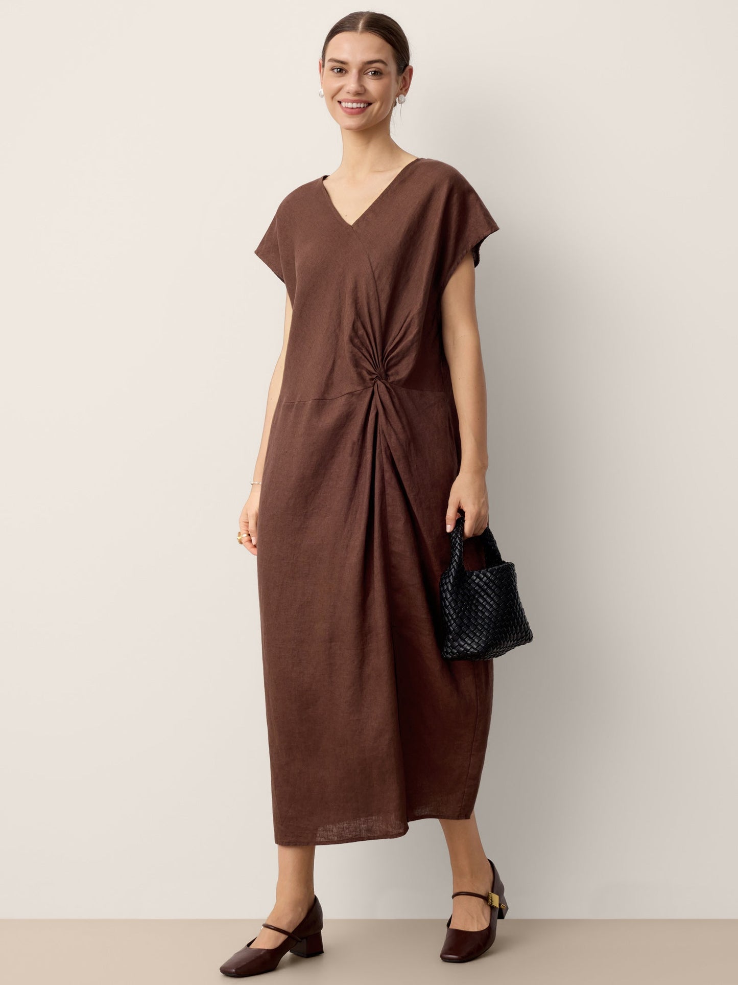 Woman wearing a brown dress with a knot detail on a plain background