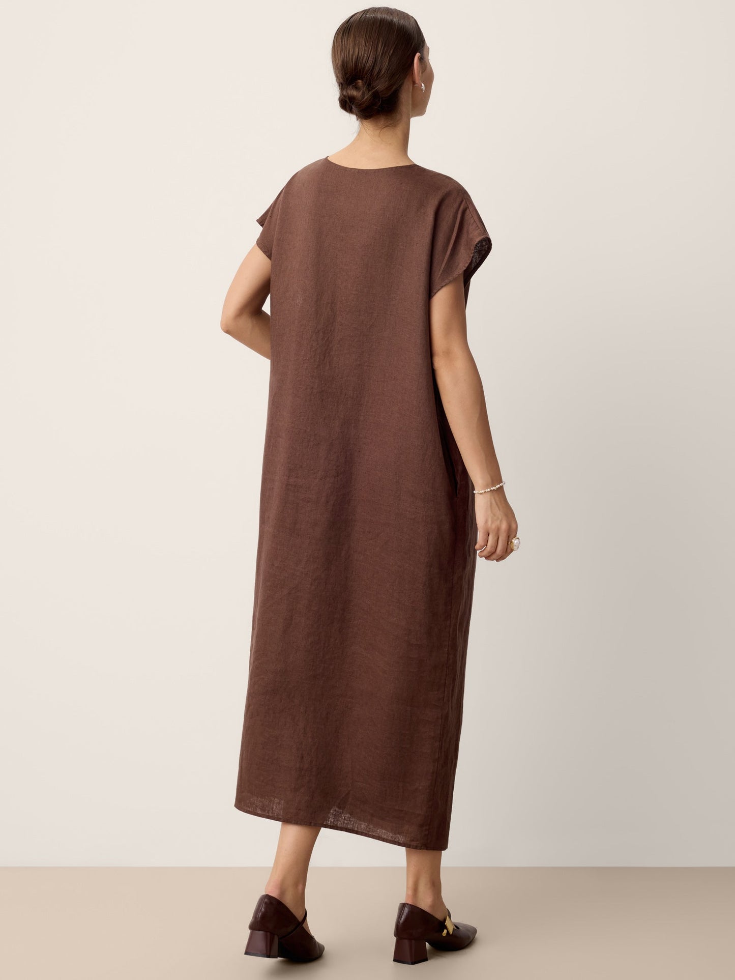 Woman wearing a brown dress against a plain background