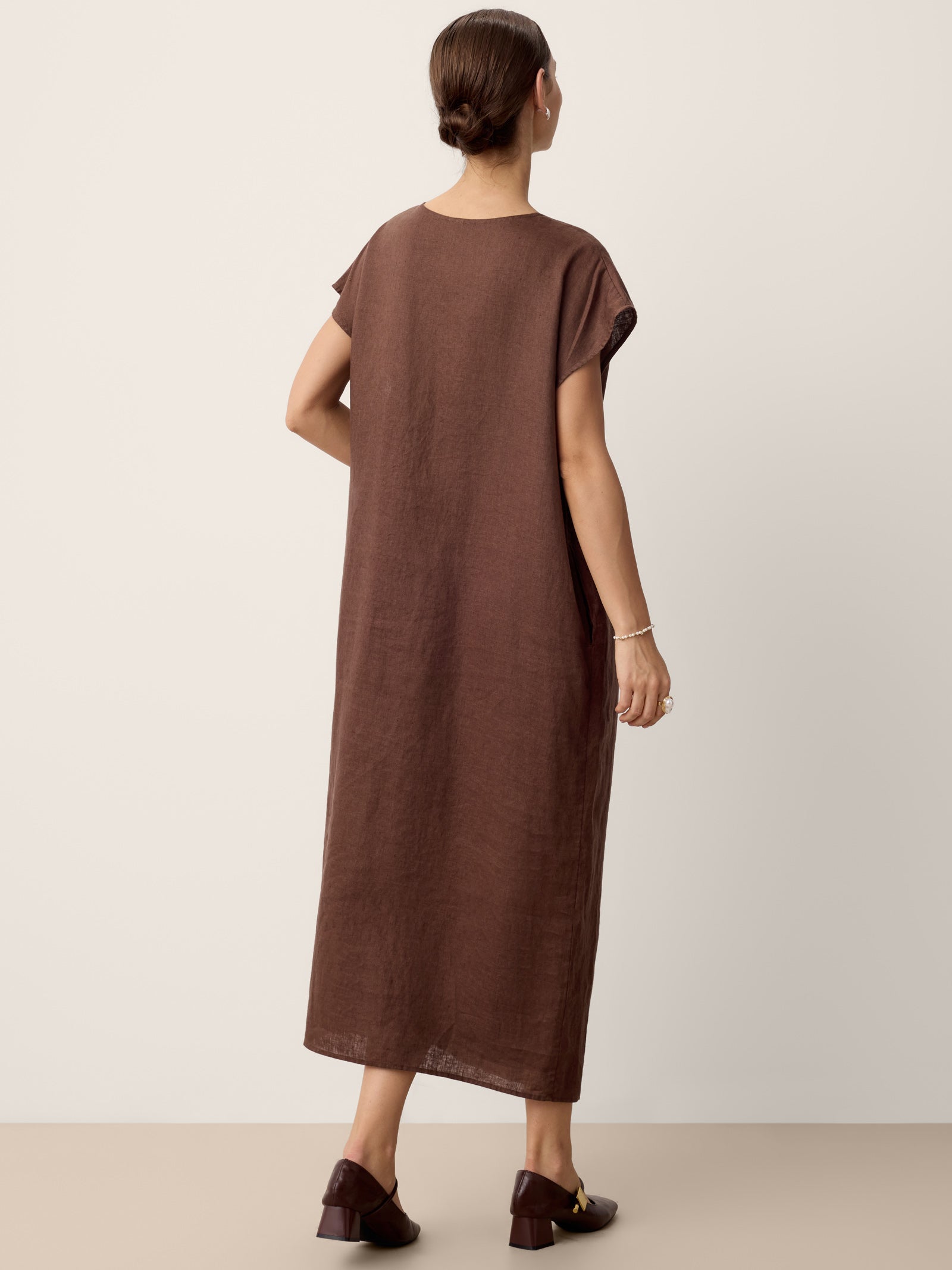 Woman wearing a brown dress against a plain background