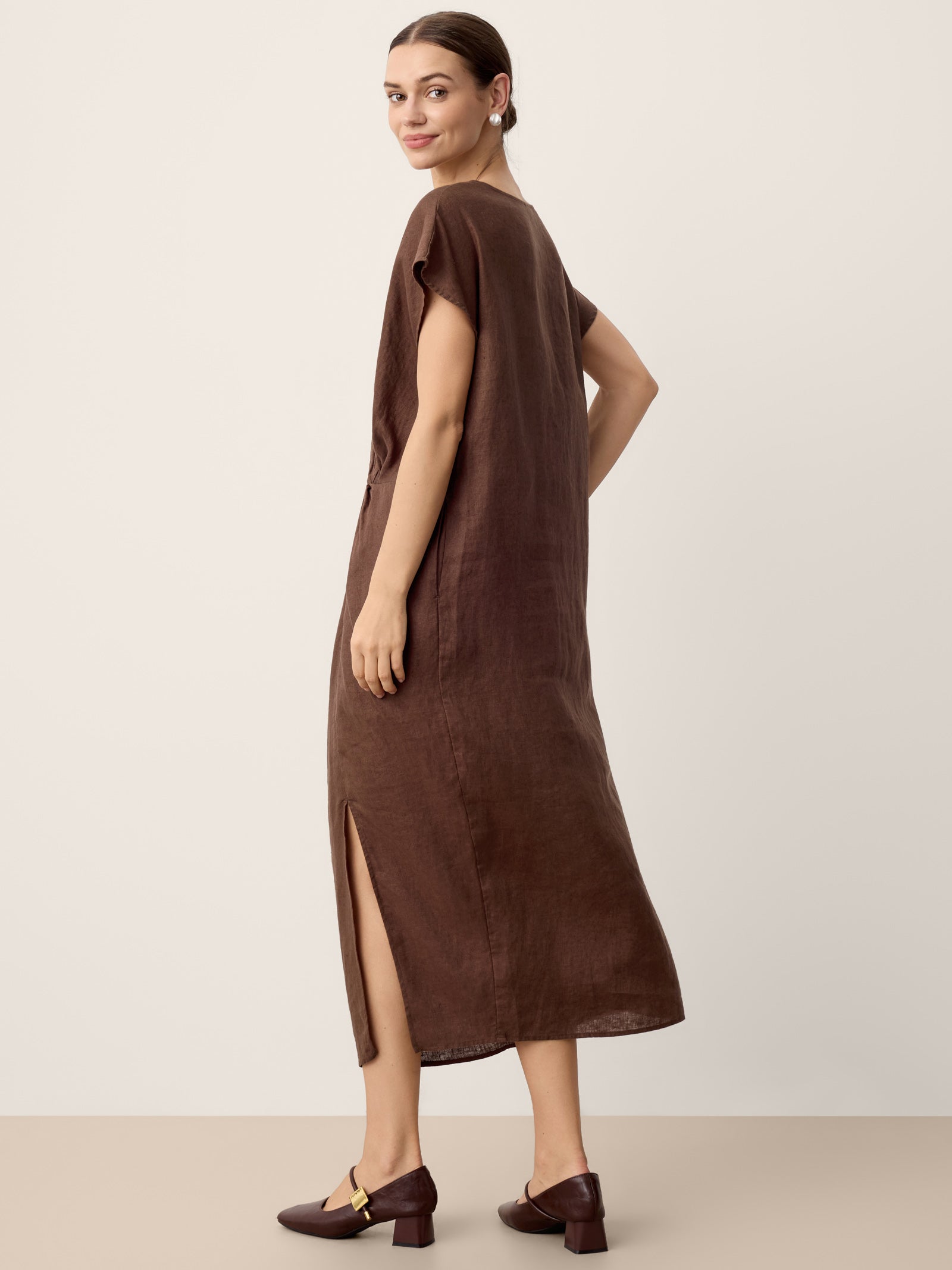 Woman wearing a brown dress with a slit on a plain background