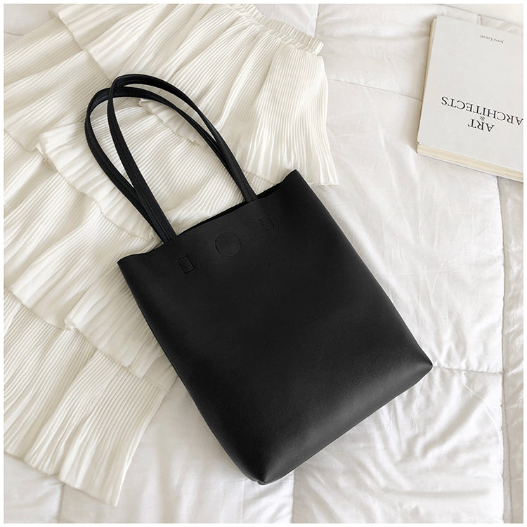 Black tote bag on a textured white surface
