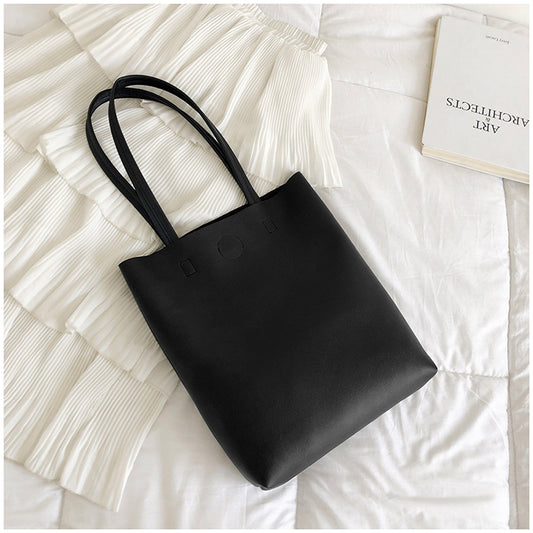 Black tote bag on a textured white surface