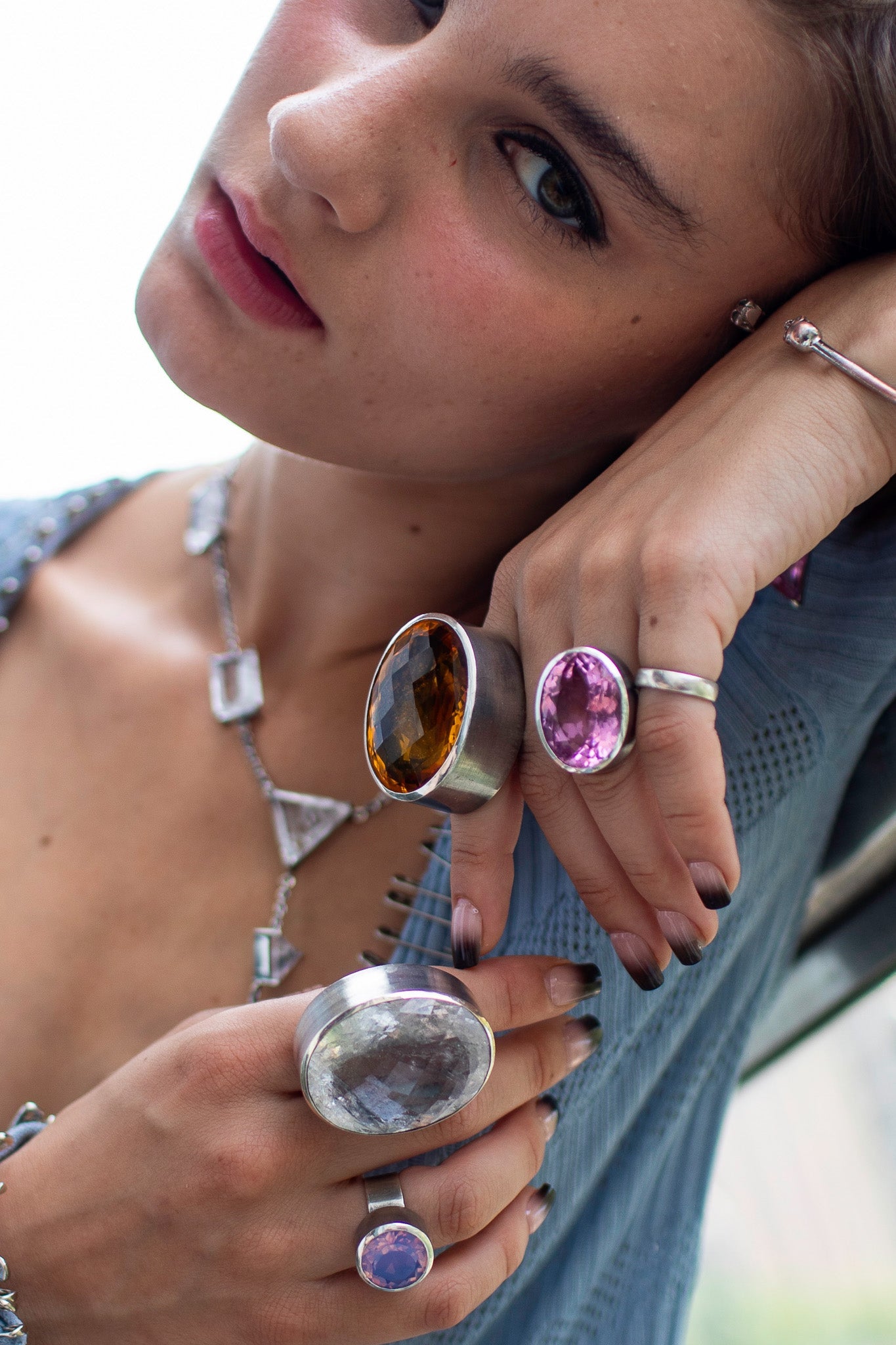 Woman wearing multiple rings with gemstones and a necklace.