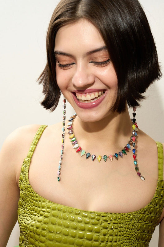 Woman wearing a colorful beaded necklace and green top against a plain background