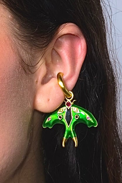 Green butterfly earring worn by a person with dark hair.
