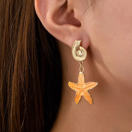 Gold starfish earring worn by a person with brown hair.