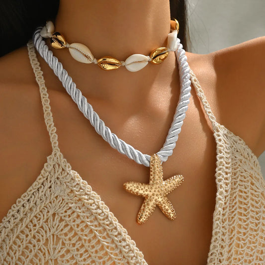 Necklace with starfish pendant and shell elements on a person wearing a crochet top.