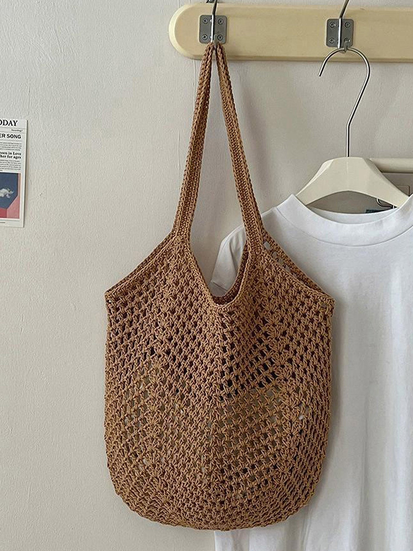 Brown woven bag hanging on a hook with a white shirt in the background.