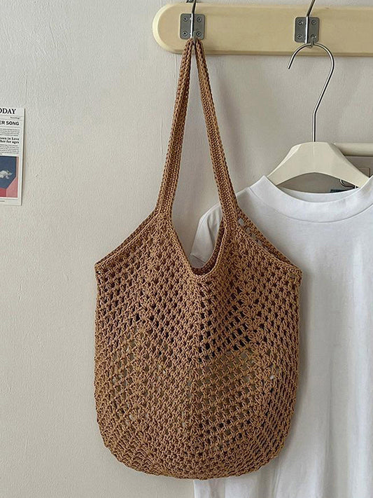 Brown woven bag hanging on a hook with a white shirt in the background.