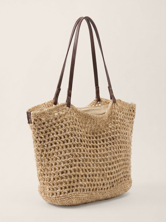 Woven straw tote bag with brown handles on a light beige background
