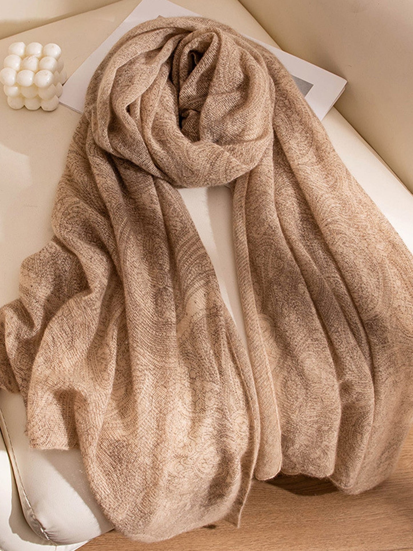 Beige scarf on a white surface with a soft focus background