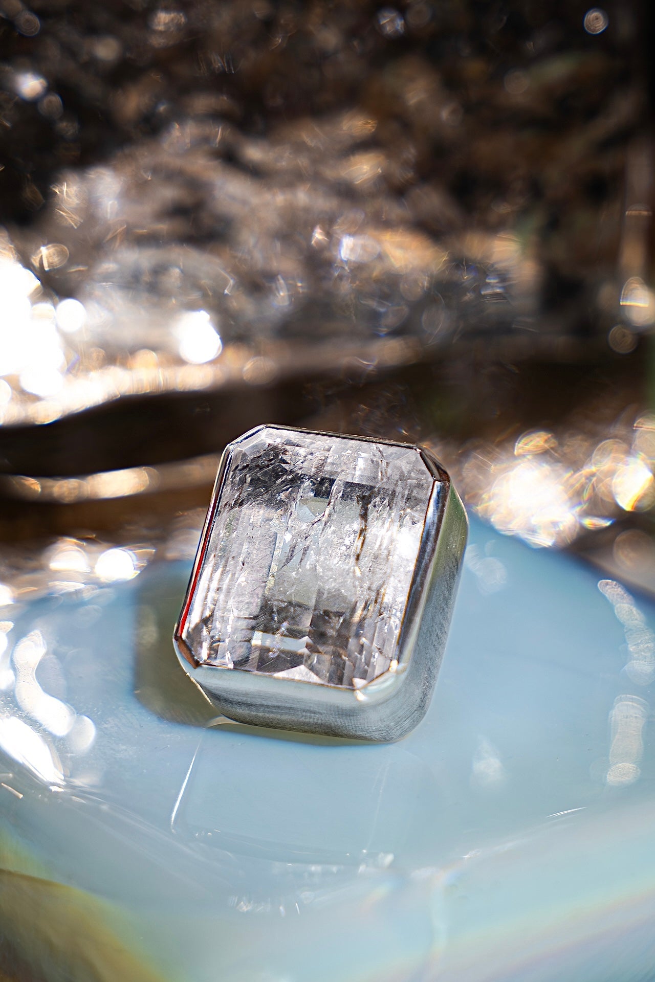 Faceted crystal on a light blue surface with blurred background