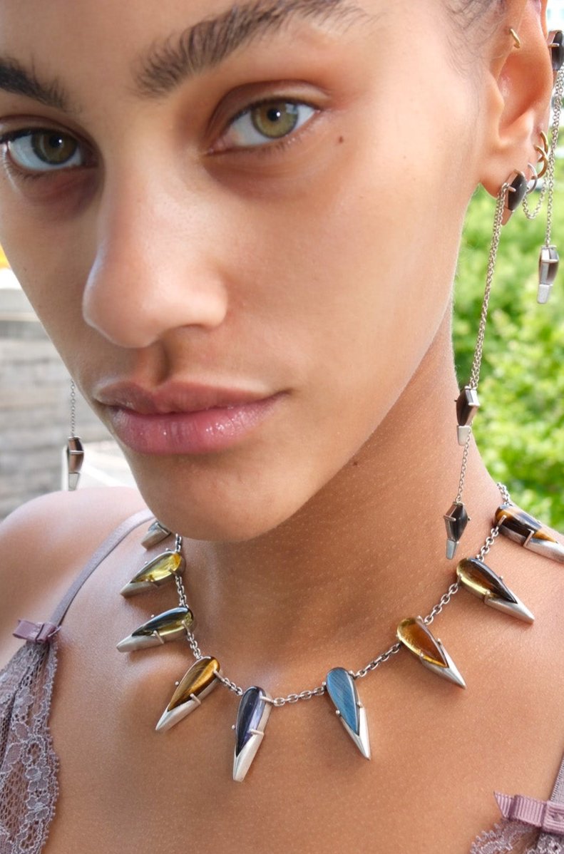 Close-up of a woman wearing a unique necklace with spike-like pendants.