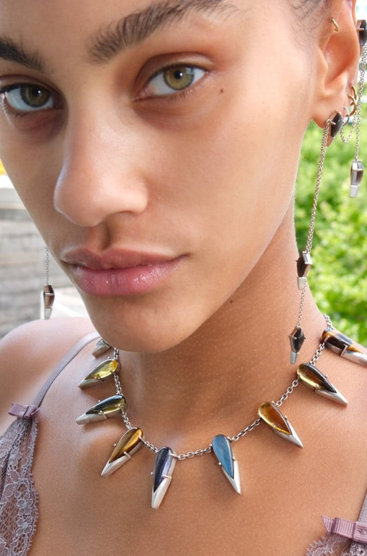 Close-up of a woman wearing a unique necklace with spike-like pendants.