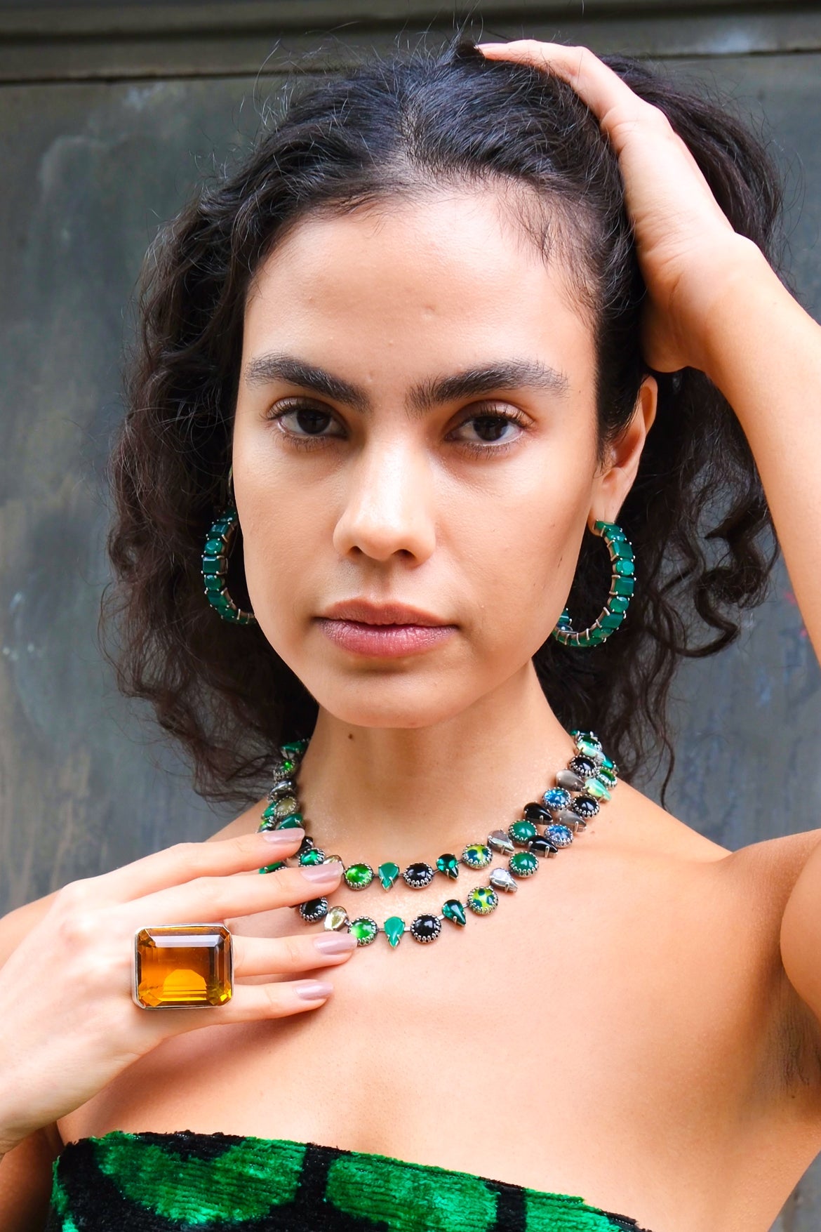 Woman wearing green jewelry against a neutral background