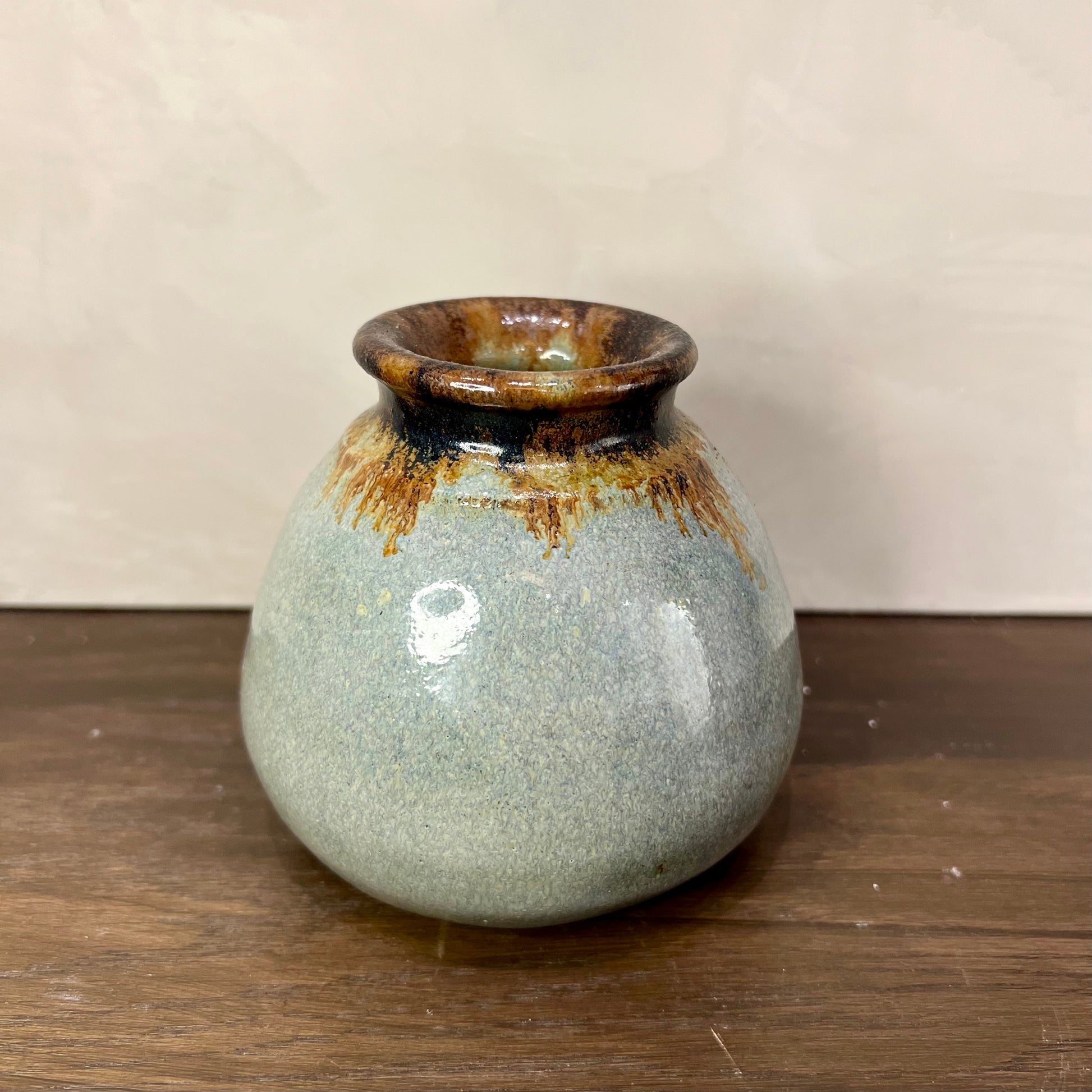 Small ceramic vase with brown and black accents on a wooden surface