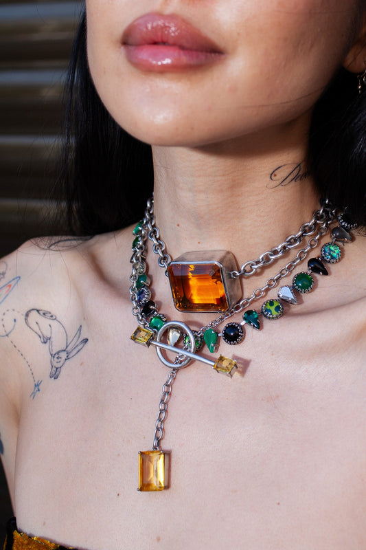 Close-up of a person wearing a colorful necklace with gemstones and a pendant.