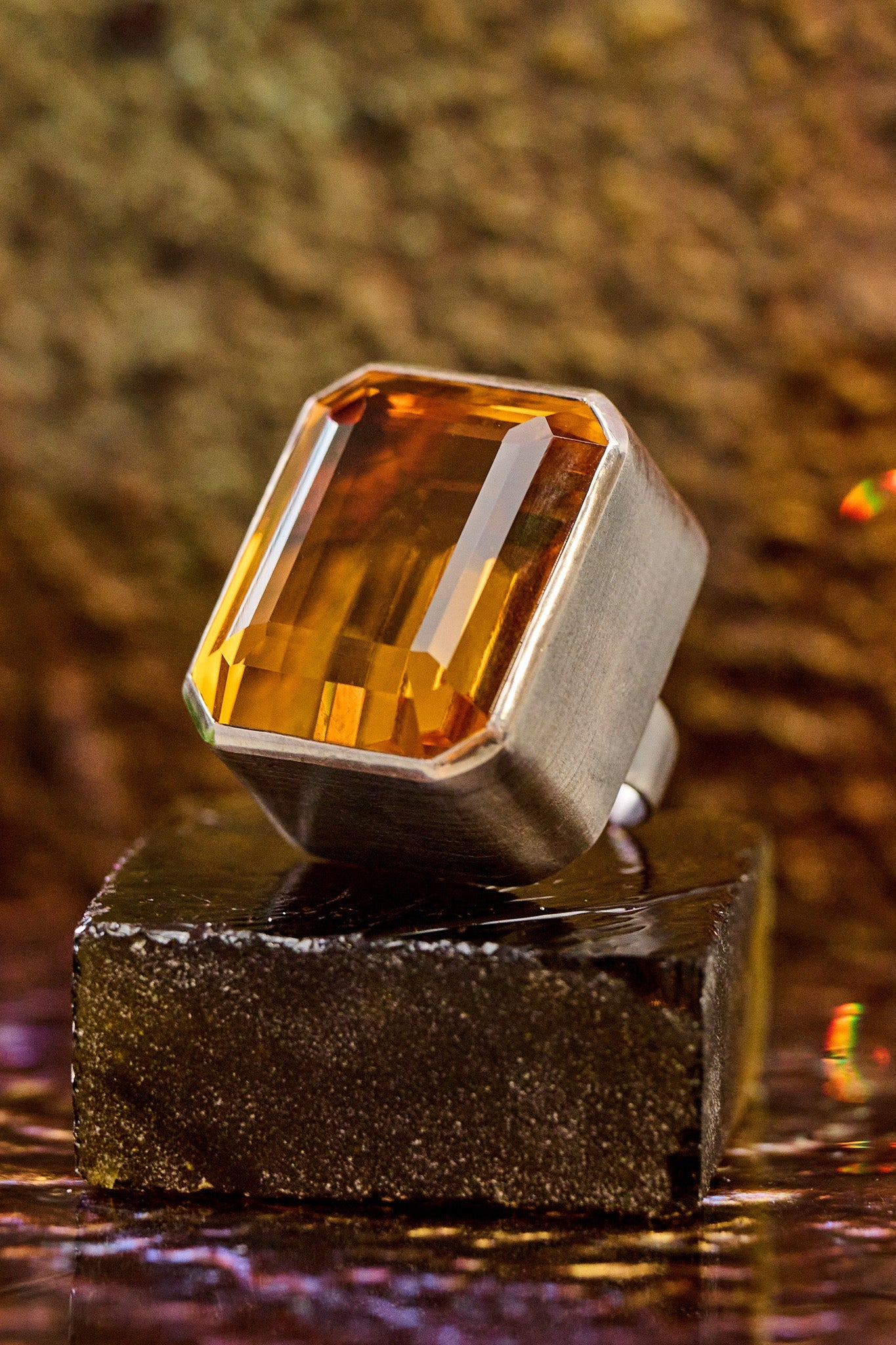 Ring with a large orange gemstone on a reflective surface