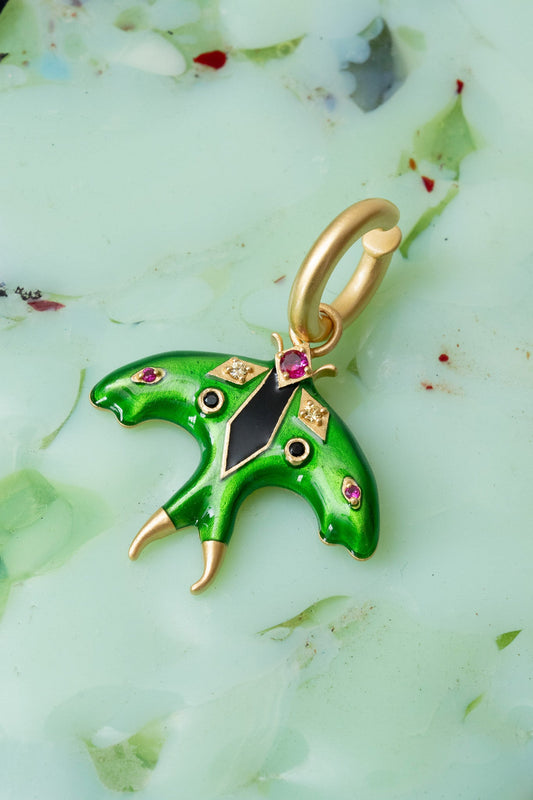 Green butterfly pendant with gold and gemstone accents on a light green background