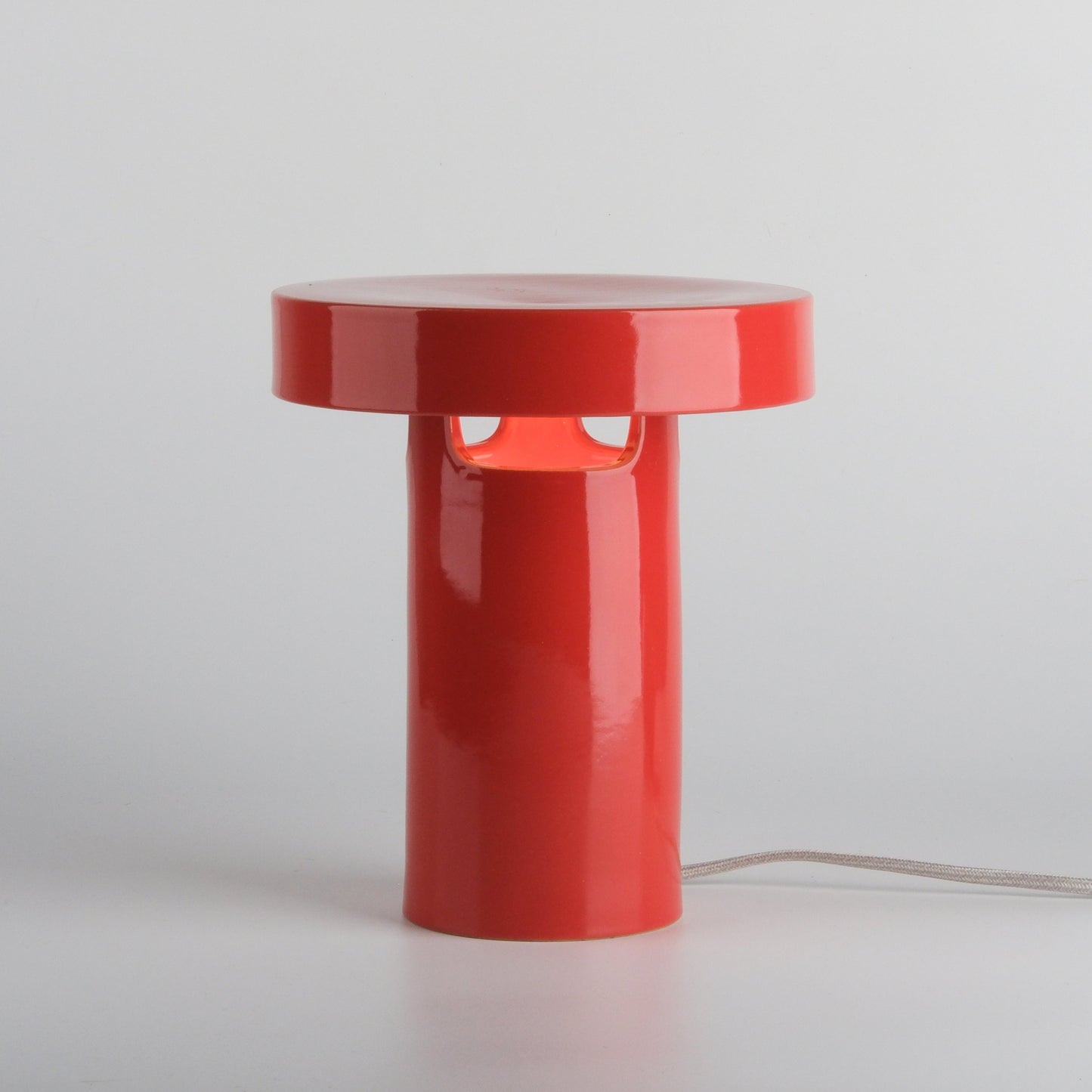 Red cylindrical lamp on a light gray background