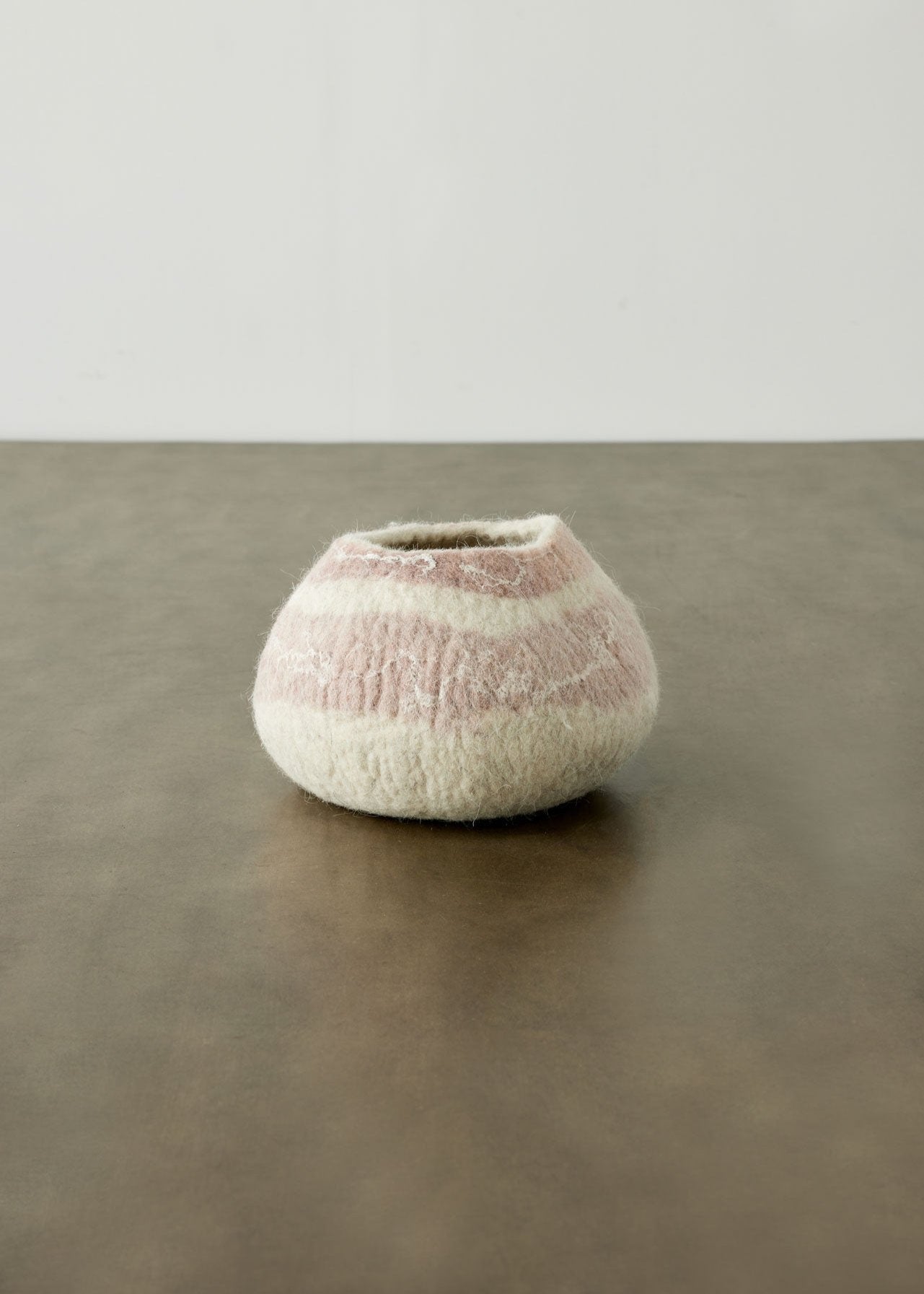 Textured ceramic vase on a reflective surface with a neutral background