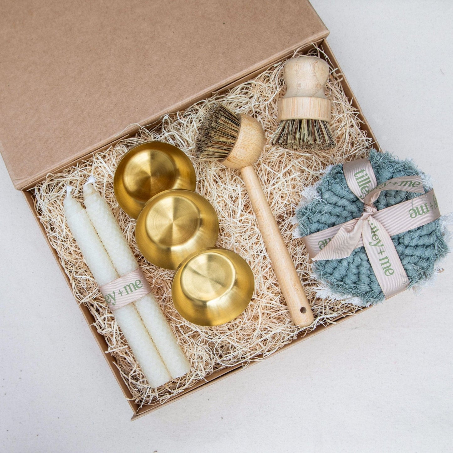 Set of gold bowls, a brush, and a blue scrubber in a gift box on a white background