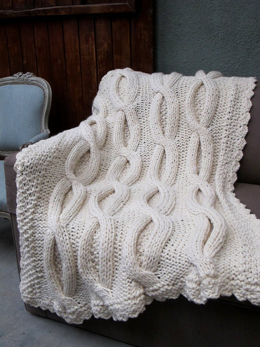 Knitted blanket draped over a sofa with a chair in the background