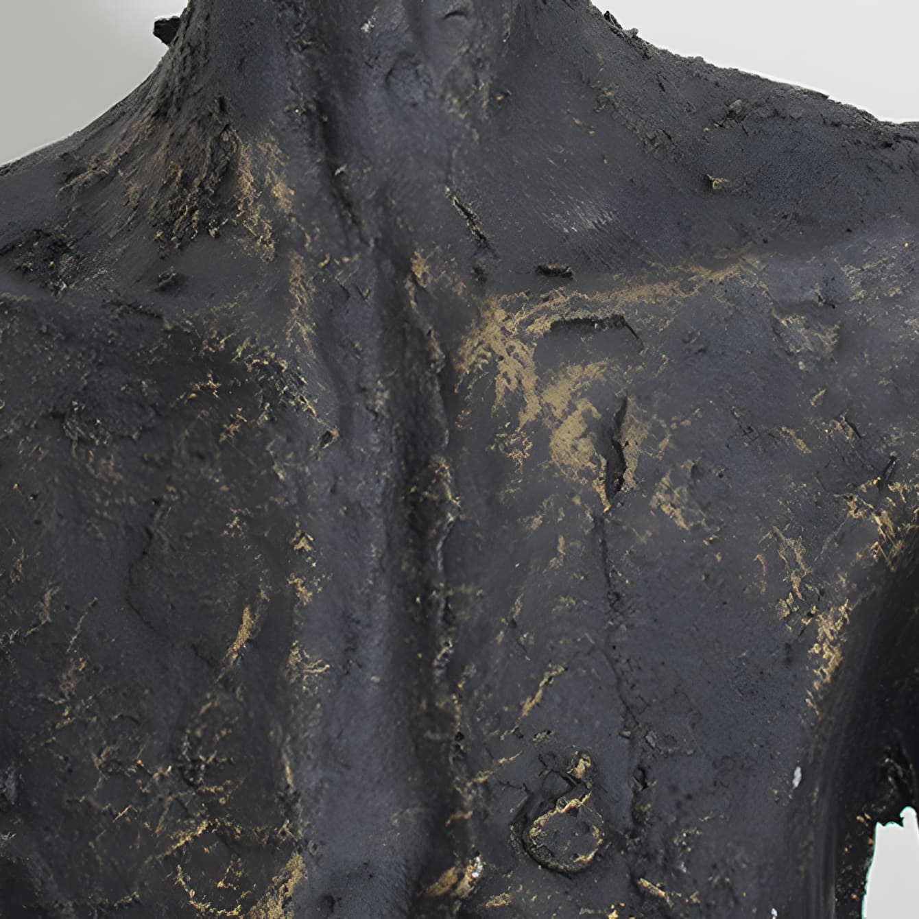 Close-up of a textured black sculpture with gold accents