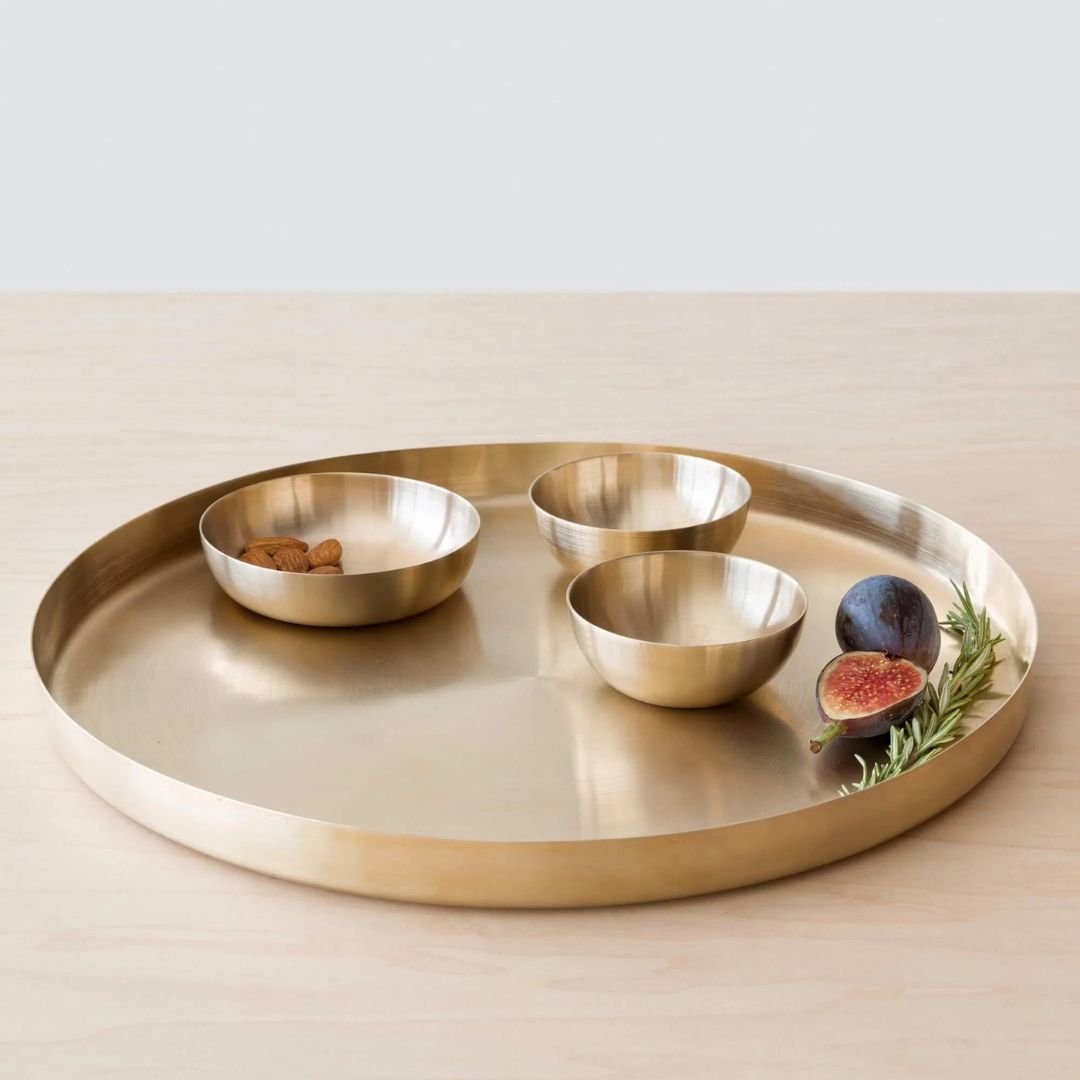 Gold tray with three small bowls and figs on a light background