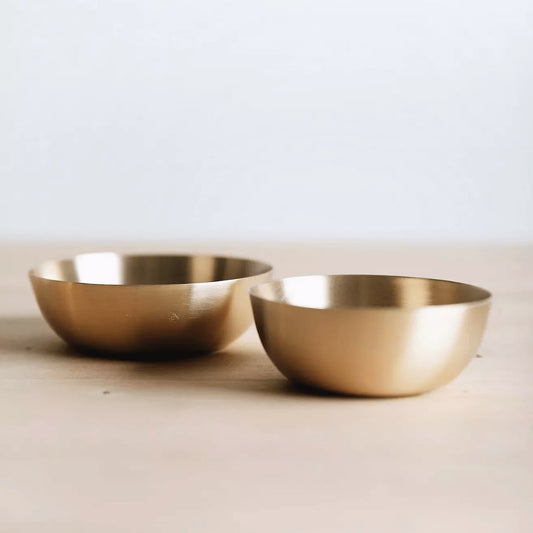 Two brass bowls on a light background