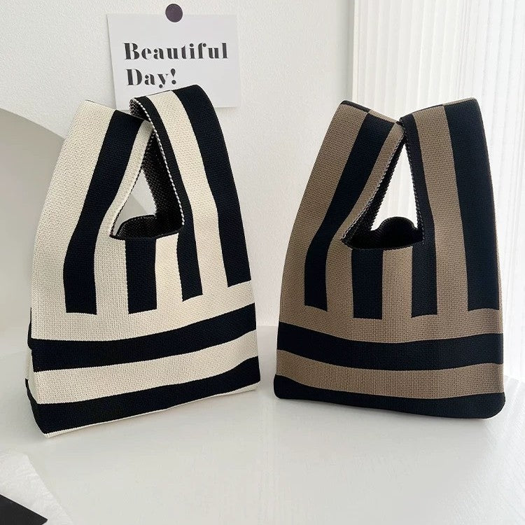 Two striped bags on a white surface with a 'Beautiful Day!' sign in the background.