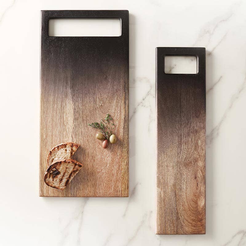 Two wooden cutting boards on a marble surface with a slice of bread and olives.