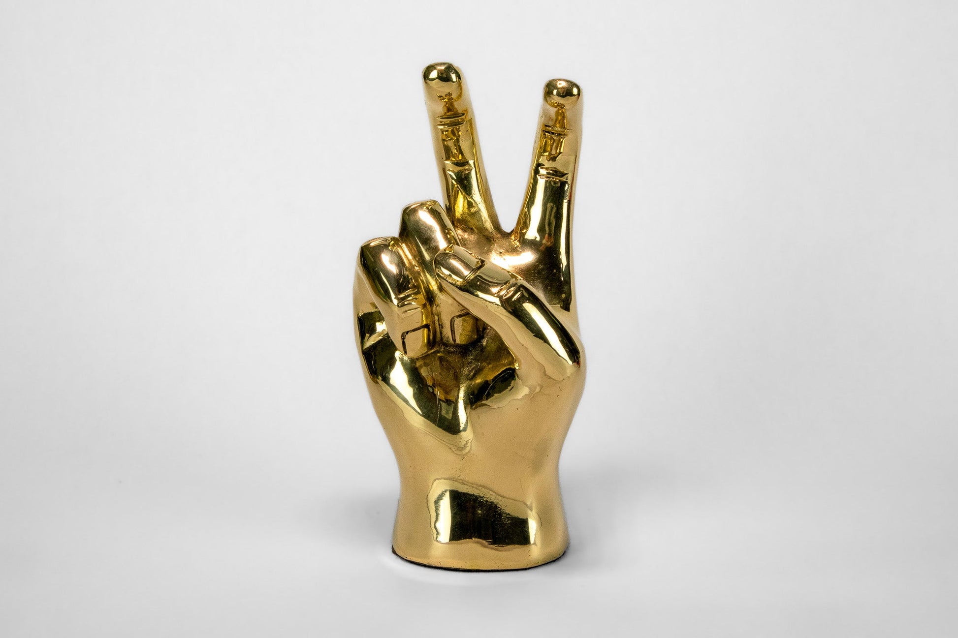Gold hand making a peace sign on a white background