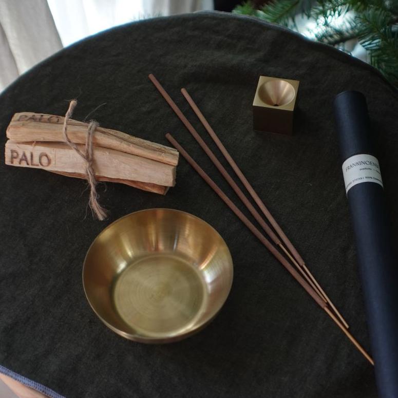 Incense sticks, a brass bowl, and other items on a dark surface